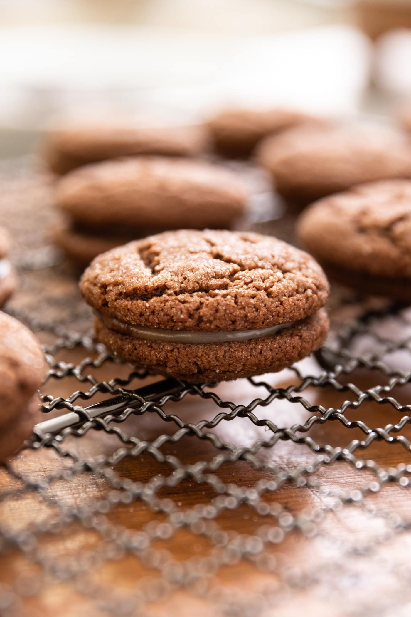 Side view of sandwich cookie sitting on cooling rack with mint filling all on wood surface