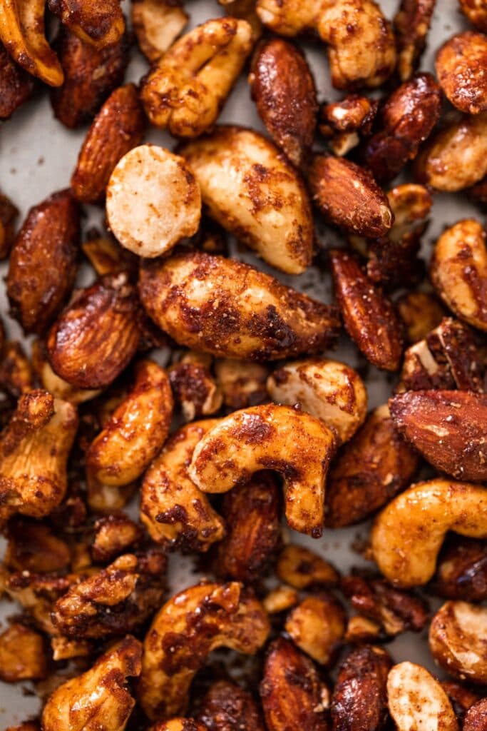 Top down close up view of spiced nuts sitting on silver baking dish
