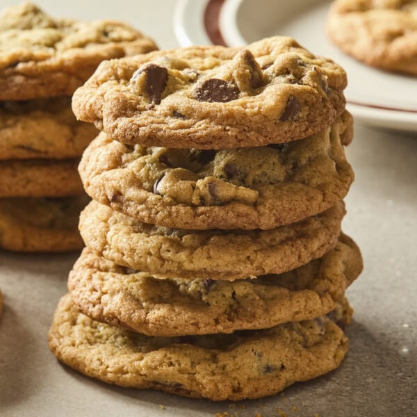 Stack of chocolate chip cookies with more cookies in the background.