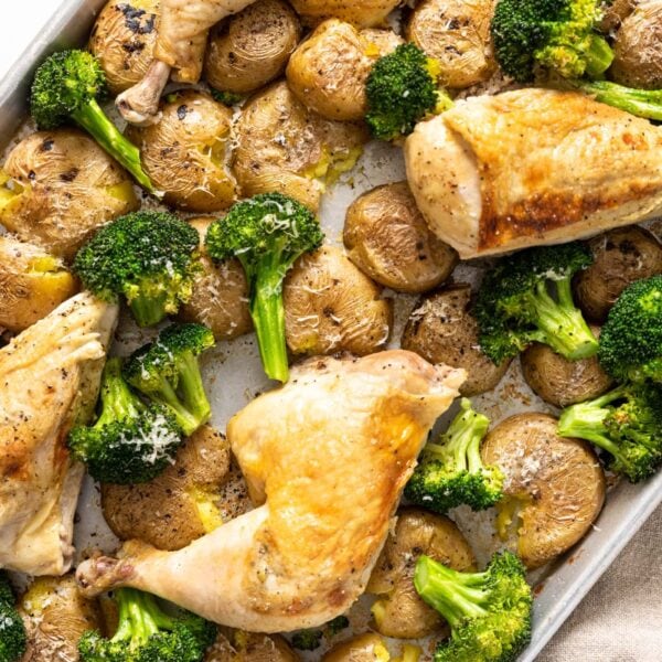 Top down view of roasted chicken breasts sitting amongst broccoli and potatoes all on sheet pan