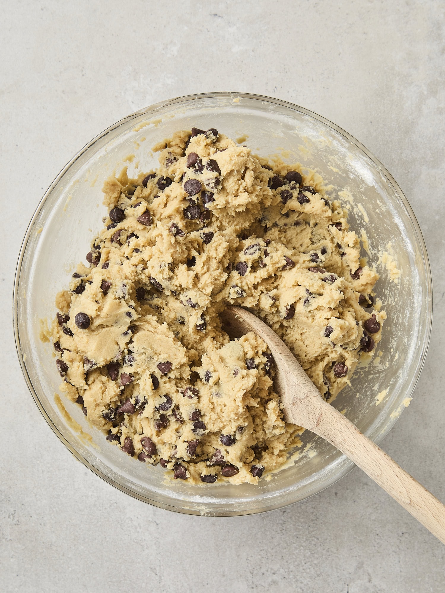Bowl with dough for cookies with chocolate chips inside.