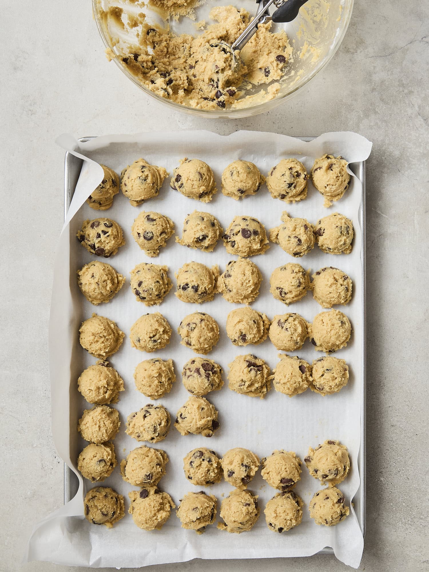 Dough balls for chocolate chip cookies on a baking sheet.