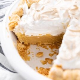 White pie plate filled with butterscotch pie with whipped cream topping browned on top.
