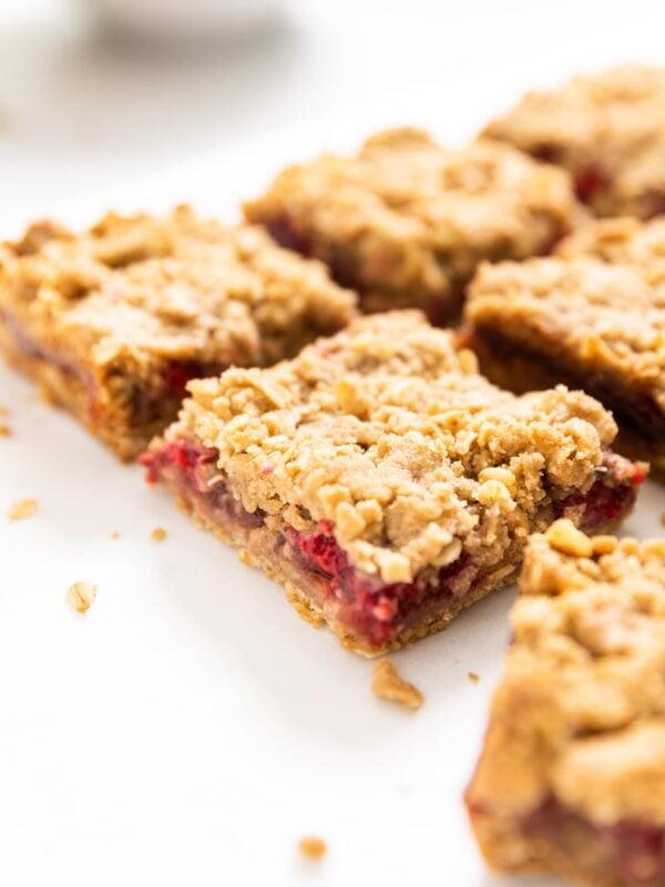 Crumb bars cut into slices filled with raspberry filled all on a white countertop