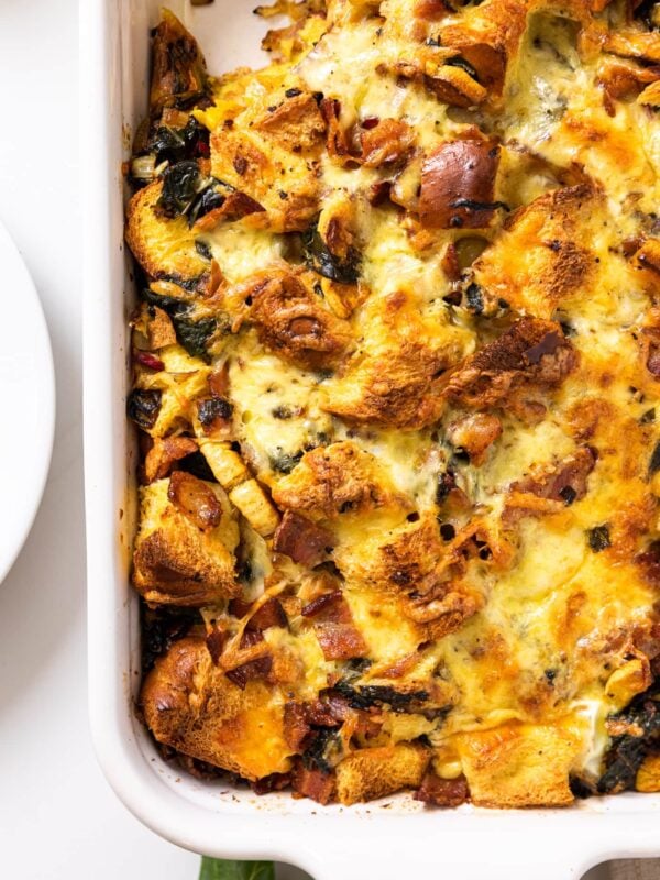 Top down view of white casserole dish sitting on white countertop filled with brown colored casserole with spoonful removed