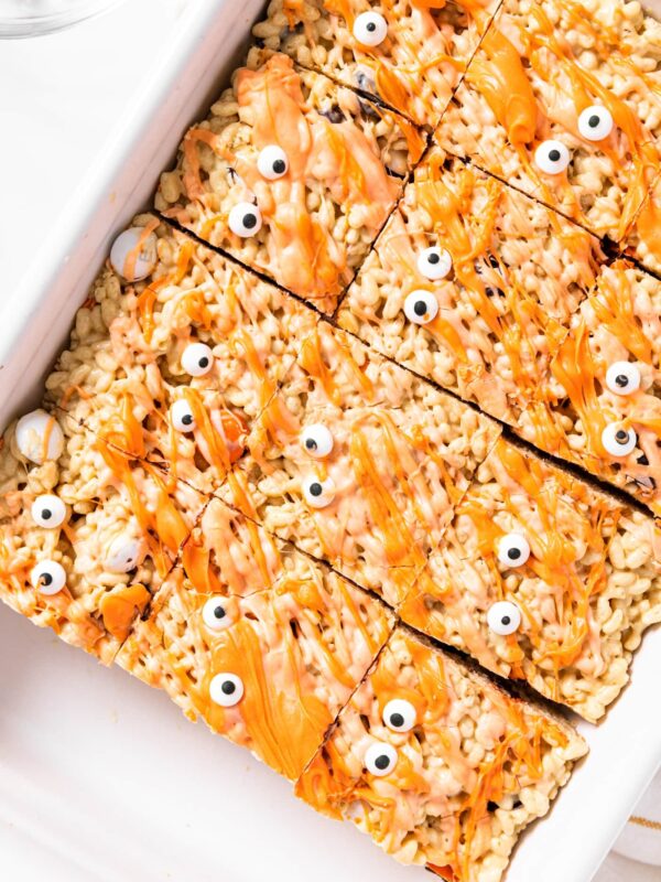 Top down view of white pan filled with peanut butter Rice Krispie treats topped with orange colored white chocolate and google eyes