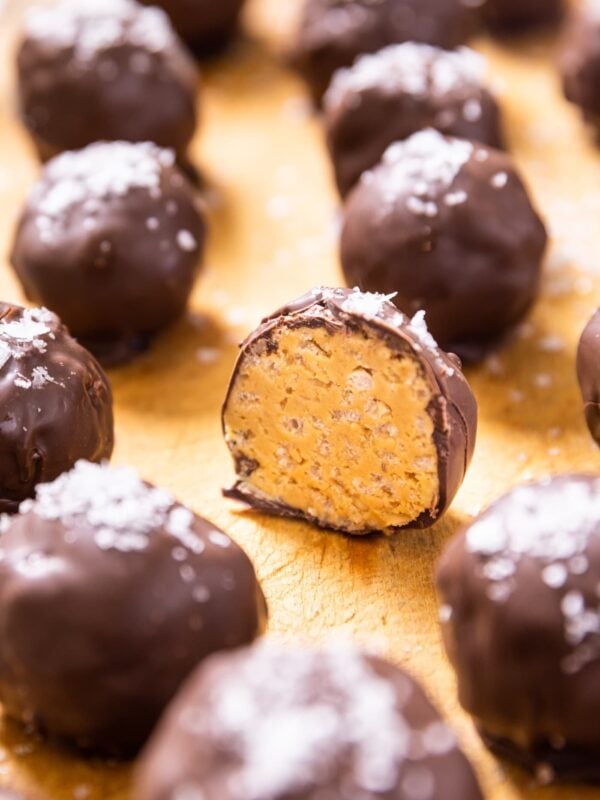 Peanut butter ball sliced in half sitting on wood board amongst other chocolate covered peanut butter balls