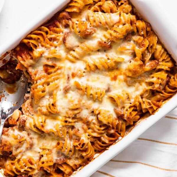 Top down view of white baking dish filled with pasta with red sauce and cheese all over the top with spoon sitting in dish