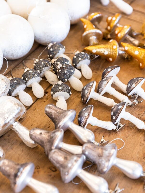Lots of various silver and gold colored mushroom ornaments sitting on wooden table