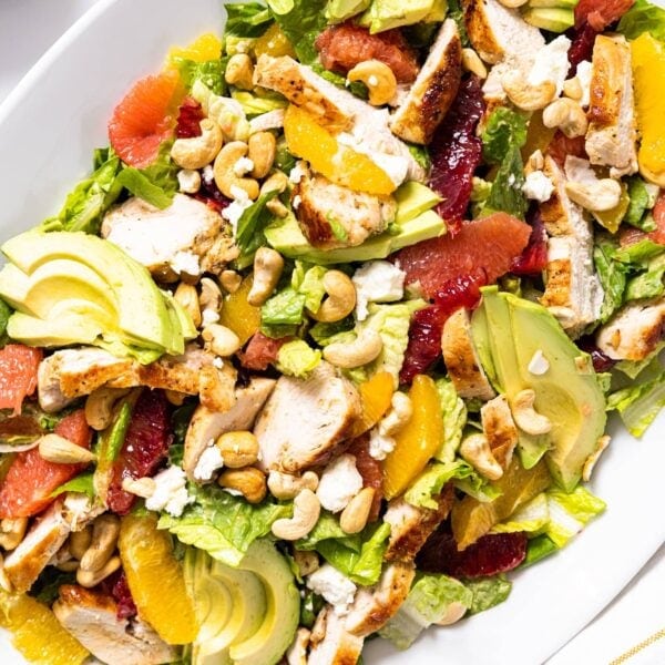 Top down view of white serving platter filled with citrus chicken salad topped with orange and grapefruit slices and cashews