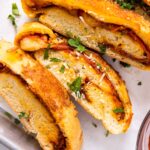 Top dow view of slices of stromboli sitting on white piece of parchment paper with parsley and Parmesan cheese on top