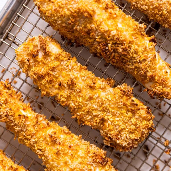 Top down view of baked crispy chicken strips sitting on wire cooling rack after being taken out of the oven