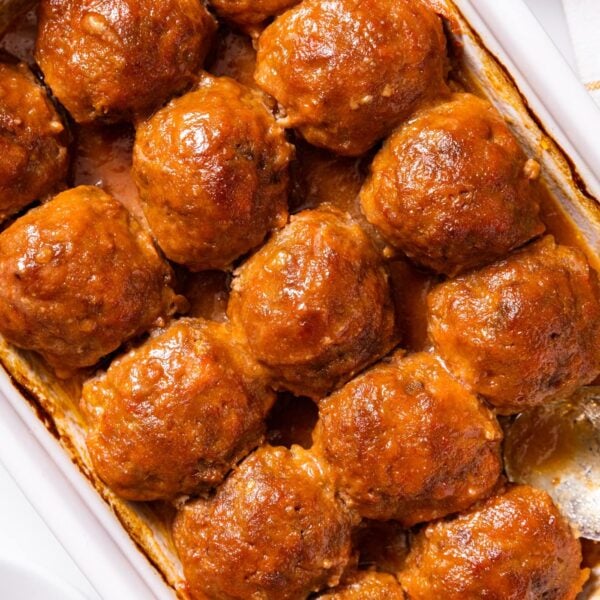 Top down view of white baking dish with ham balls sitting in dish after being baked with brown colored sauce over top