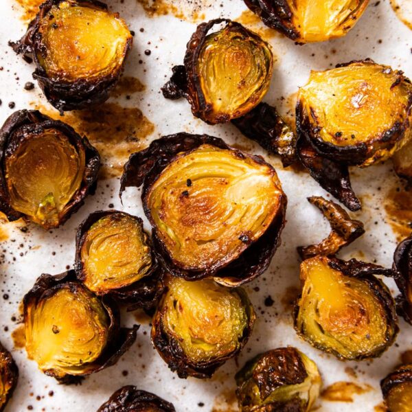 Top down view of crispy Brussels sprouts sitting on parchment paper after being fried in the oven