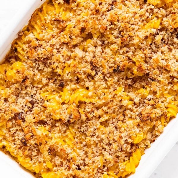 White baking dish filled with baked Sungold pasta with breadcrumbs all over the top sitting on white marble surface.