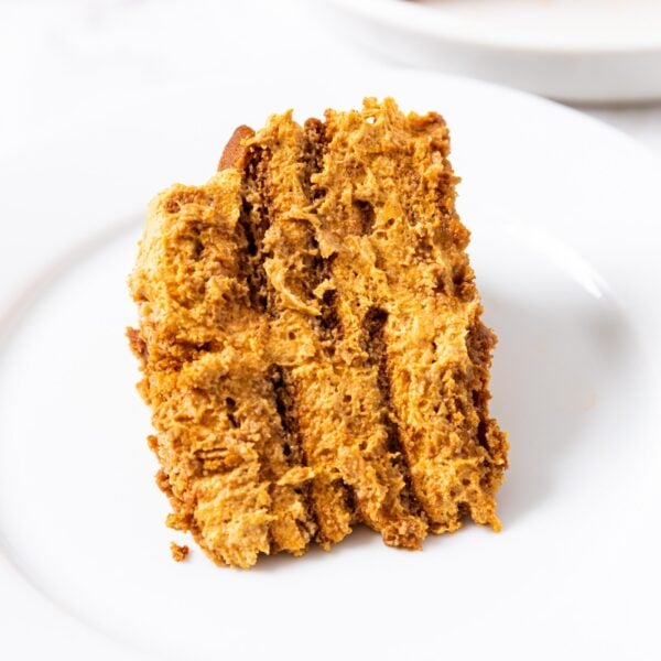 White plate with slice of pumpkin icebox cake showing interior layers with rest of icebox cake in background.
