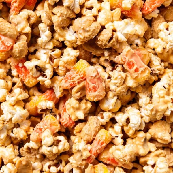 Candy corn and peanuts covered in peanut butter mixture mixed with popcorn all sitting on a baking sheet.