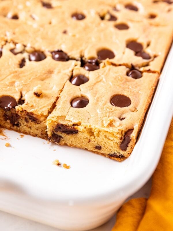 White baking dish filled with baked blondies showing interior texture as well as chocolate chips sprinkled throughout.