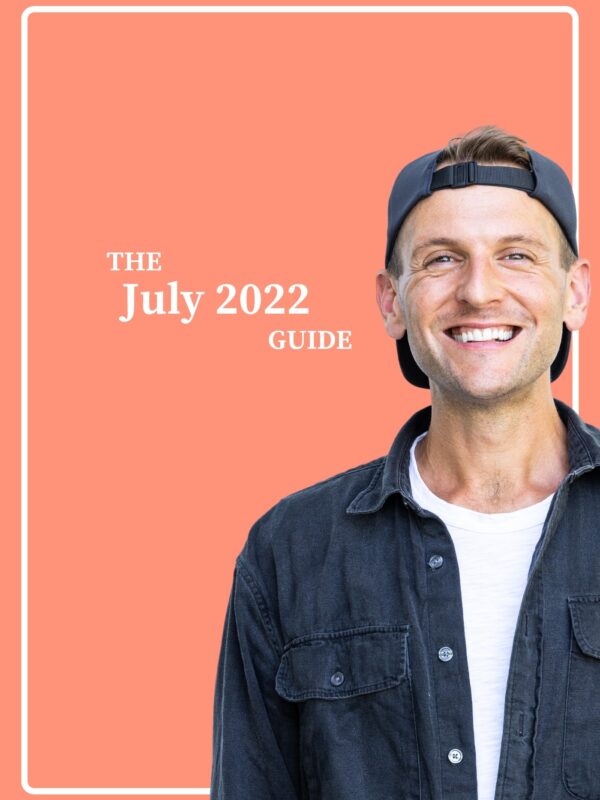 Man standing in front of pink background wearing black shirt and black backwards hat.