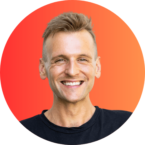 Kaleb Wyse wearing black shirt standing in front of a red and orange gradient background smiling.