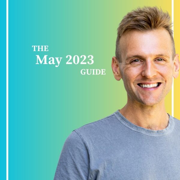 Kaleb Wyse wearing a gray shirt standing in front of a blue and yellow gradient background while smiling.