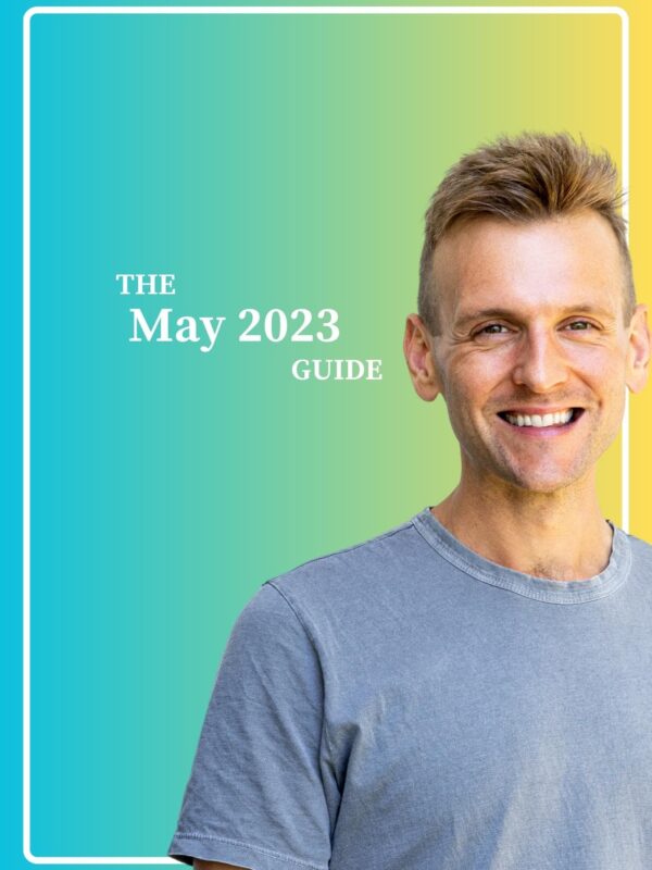 Kaleb Wyse wearing a gray shirt standing in front of a blue and yellow gradient background while smiling.