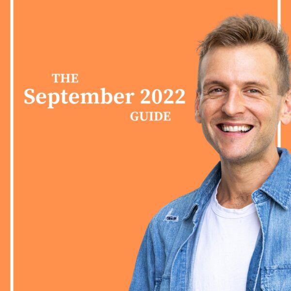 Kaleb Wyse wearing a blue denim shirt over a white shirt standing in front of bright orange background.