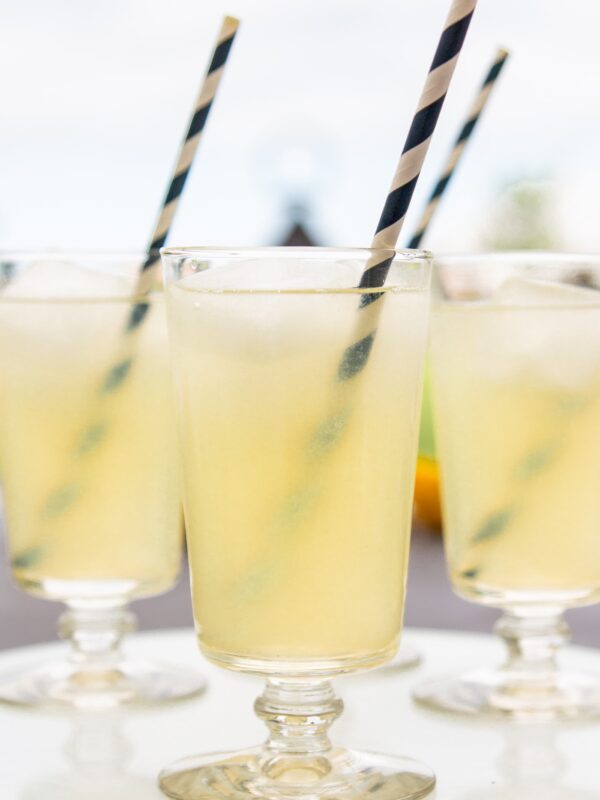 Three glasses full of yellow lemonade sit on a platter.