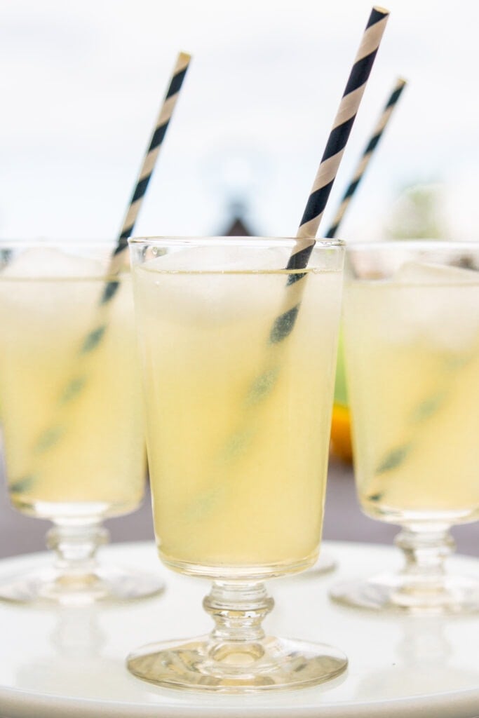 Three glasses full of yellow lemonade sit on a platter.