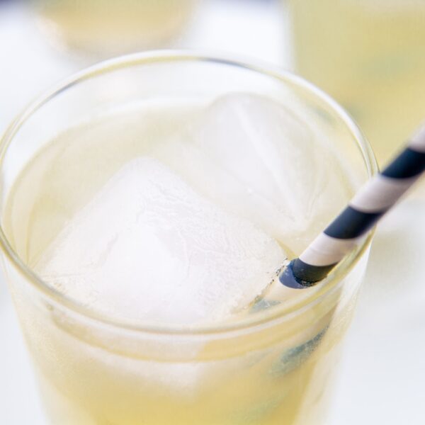 The top of a glass of lemonade with ice and a straw.