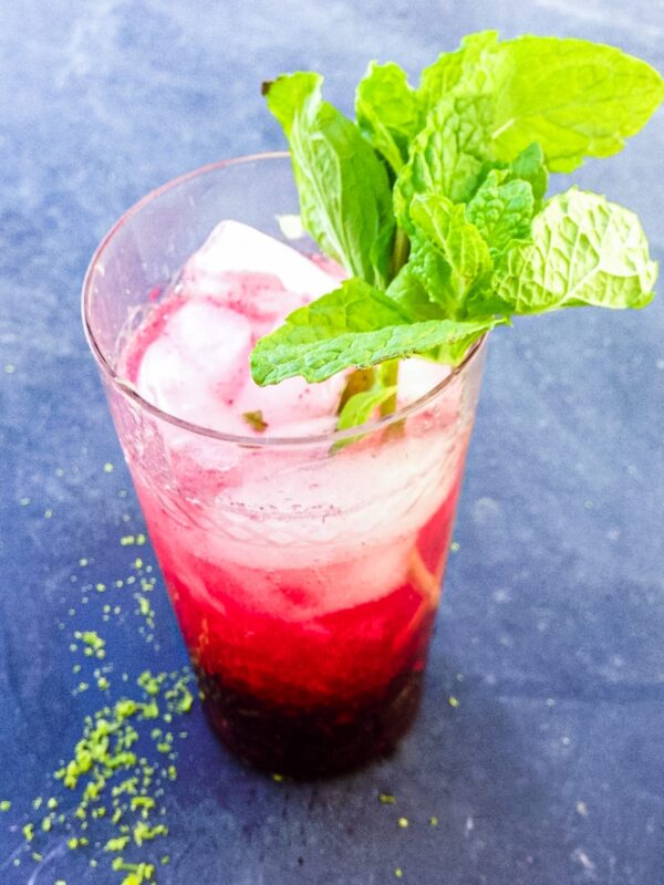 A glass full of mojito with mint sits on a table.