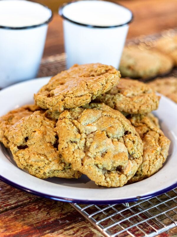 A plate stacked with cookies sit on a wooden countertop.