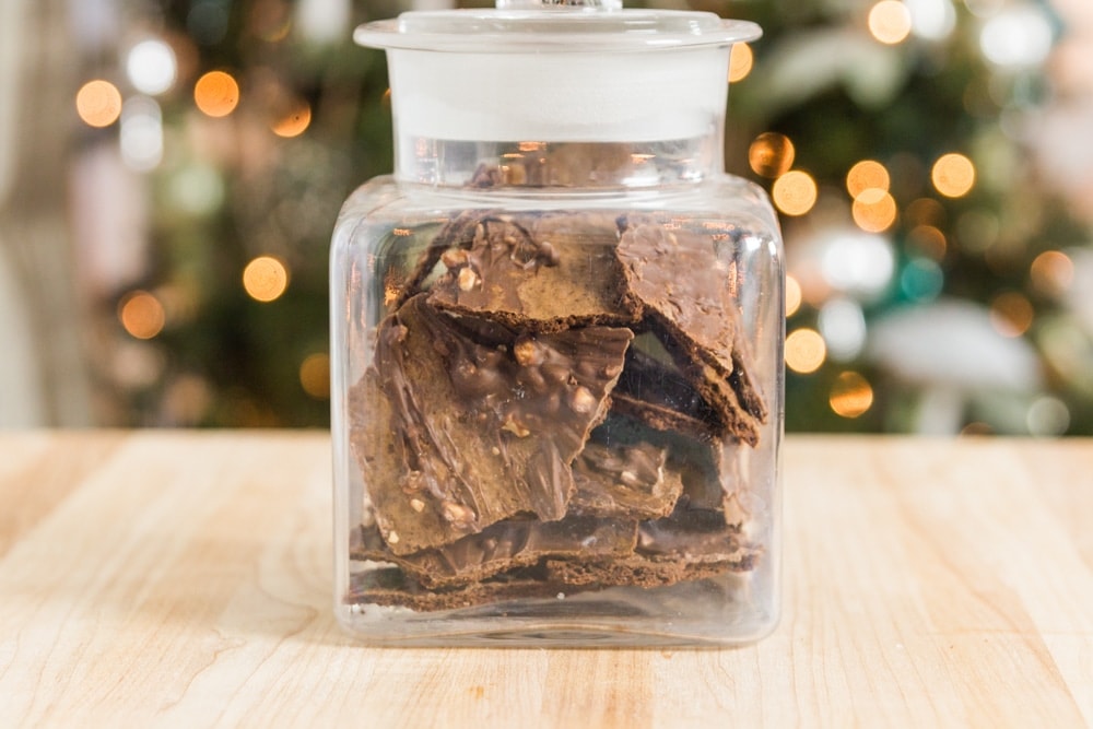 Brownie thins fill a glass jar on a table.