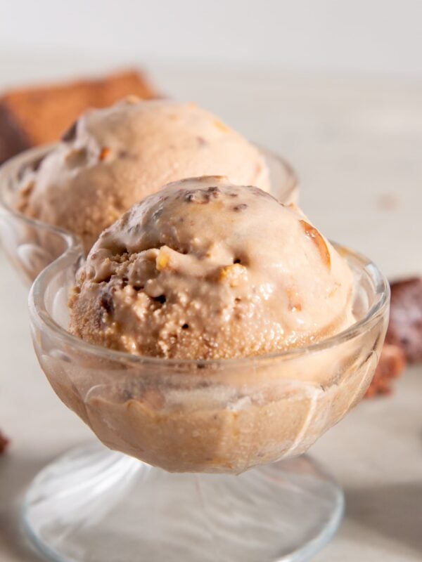 A glass container with two scoops of chocolate ice cream.