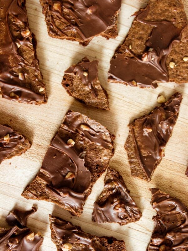 Thin chocolate brownie pieces placed on a wooden table.
