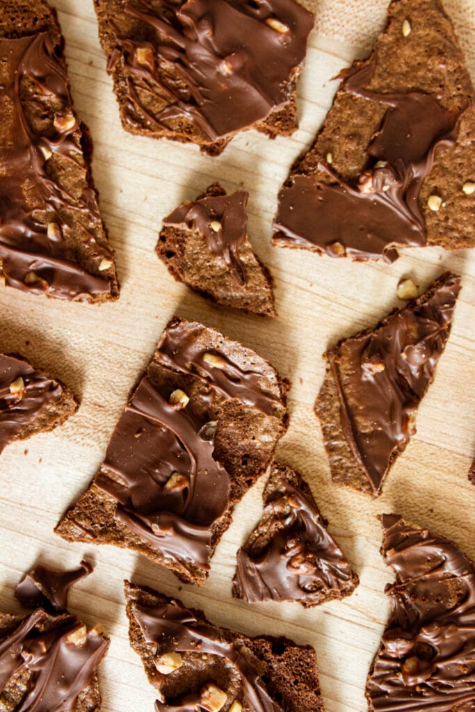 Thin chocolate brownie pieces placed on a wooden table.