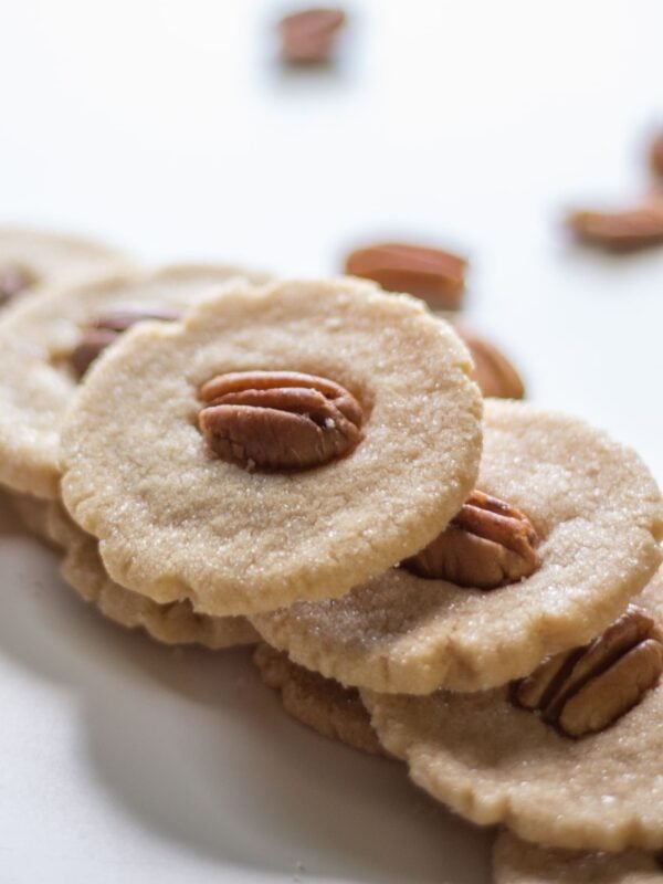 Small cookies with pecans are stacked in a pyramid.