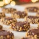 Cookies lined in rows sit on parchment paper in front of Christmas lights.