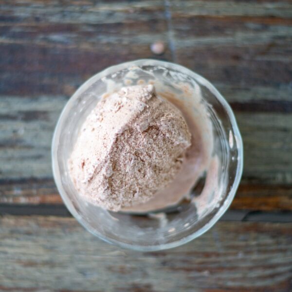 A top-down view of a scoop of chocolate ice cream in a bowl on a table.
