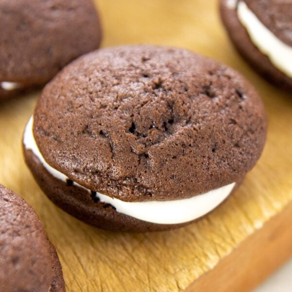 A chocolate cookie filled with cream sits on a wooden block.