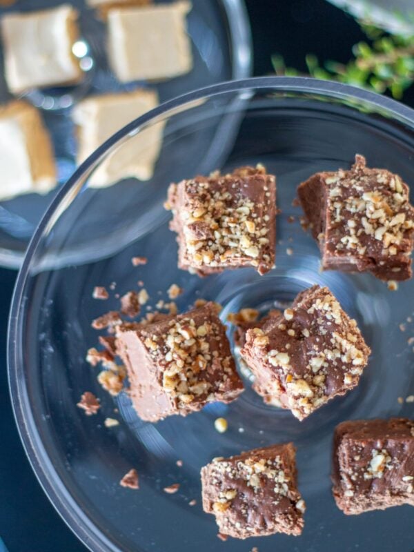 Chocolate fudge sits on a glass platter on a table.