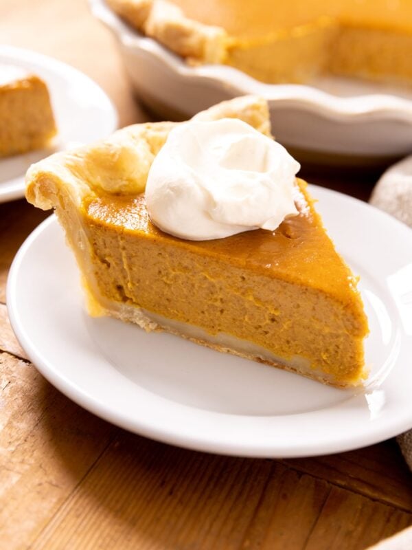 A slice of pumpkin pie rests on a plate.