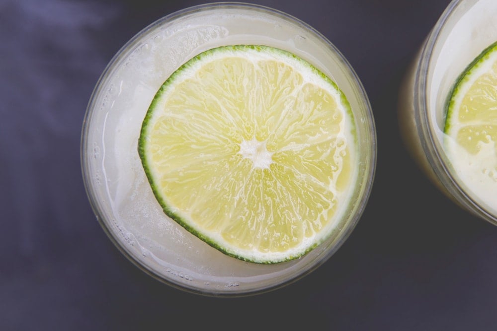 A lime slice floats on top a glass full of lemonade.