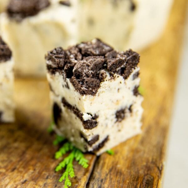 White fudge made with crushed cookies sits on a wooden block on a table.
