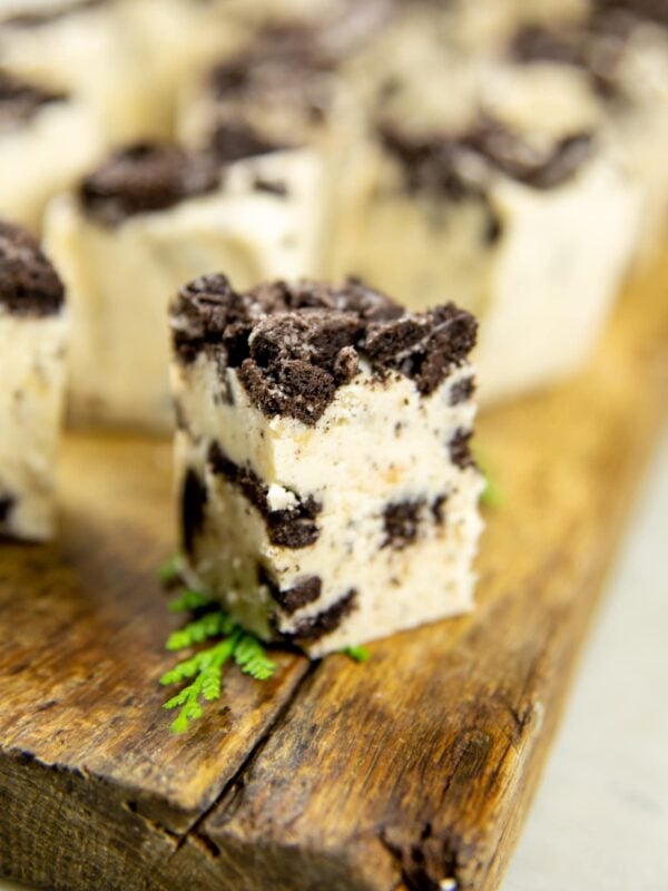 A piece of white fudge with crushed Oreos sits on a wooden block.