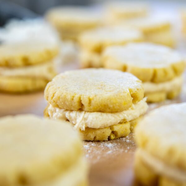 A layered cookie rests on parchment paper, surrounded by other cookies.