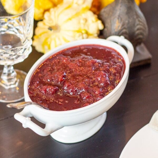 Cranberry sauce in a decorative dish rests on a table.
