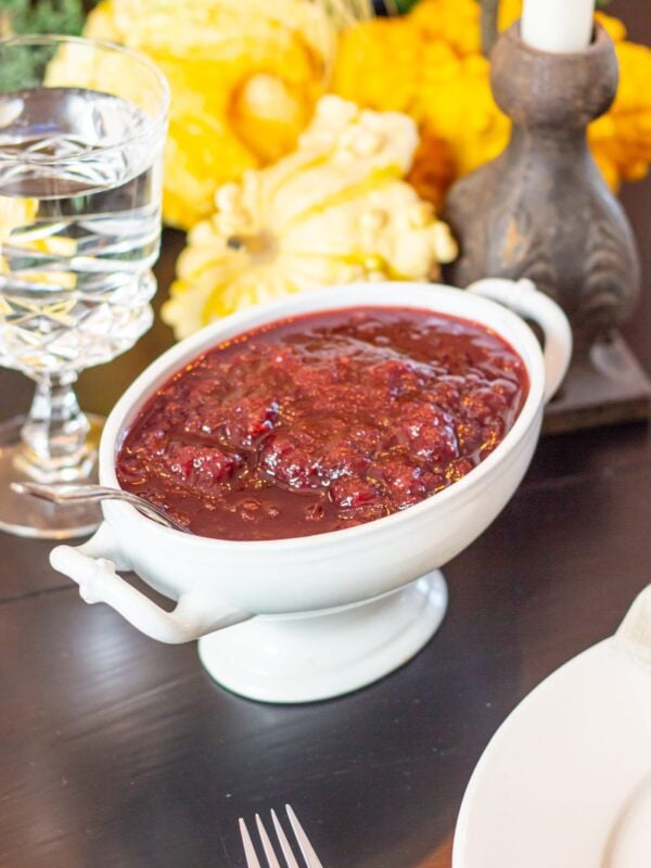 A decorative dish full of cranberry sauce rests on a table.