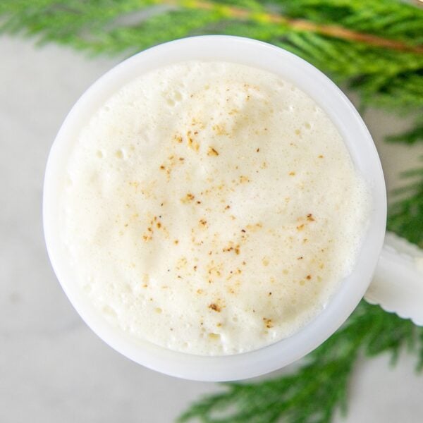 The top foam of eggnog with spices in a mug.