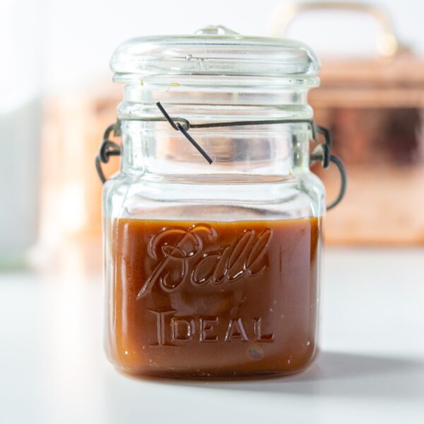 A small jar filled with homemade caramel.